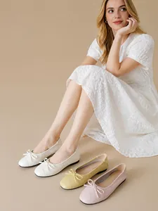 Dettaglio di ballerine a punta tonda con fiocchi in pelle bianca, beige e rosa