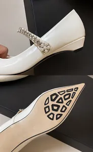 Detailed view of rhinestone pearl strap and non-slip sole of white pointed Mary Jane shoes