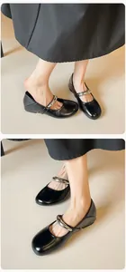 Gros plan de chaussures Mary Jane en cuir noir avec bride métallique argentée et bout rond