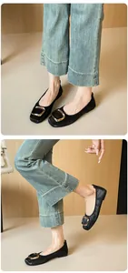 Detailansicht schwarzer Ballerinas mit goldener Schnalle und gewebter Textur