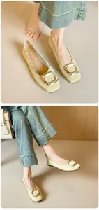 Detail von cremefarbenen flachen Schuhen mit Krokostruktur und goldener Schnalle