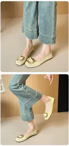 Detailaufnahme von cremefarbenen Ballerinas mit Lederstruktur und goldener Schnalle