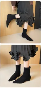 Close-up of black pointed-toe flat sock boots with textured matte suede finish