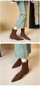 Detail of dark brown pointed toe flat sock boots paired with light blue flared jeans
