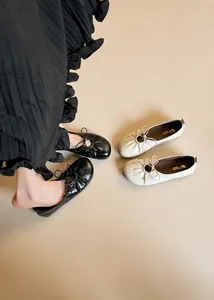 Detail of ballet flats showing soft pleated leather texture and delicate bow tie decoration