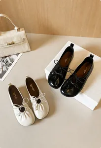 Close-up of ballet flats with bow detail and pleated texture in black and beige colors