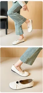 Detailed close-up of cream soft leather ballet flats with pleated toe and bow design