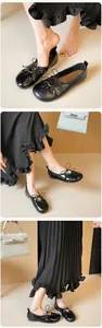 Close-up of black ballet flats featuring round toe and delicate bow detail on soft leather
