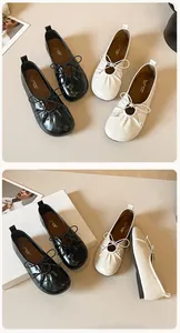 Detail of ballet flats showing round toe pleats and bow tie in black and cream