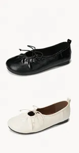 Close-up of ballet flats in black and beige with bow details and soft leather texture