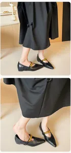 Nahaufnahme schwarzer spitzer Ballerinas mit auffälliger goldener Metallschnalle vorne