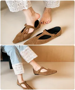 Détail de ballerines pointues en suédine marron avec bride en T et boucle métallique