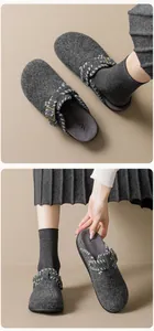 Detailed macro view of dark grey felt mules with metal buckle and woven strap design