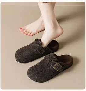 Detailed side view of brown felt clogs featuring woven strap and golden buckle on foot