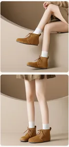 Detailed view of brown suede lace-up ankle boots with round toe and flat sole design
