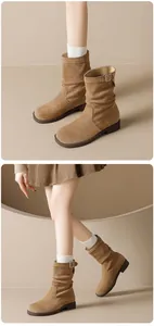 Detail der braunen Slouchy-Stiefel mit Metallschnalle und hochwertiger Wildlederstruktur