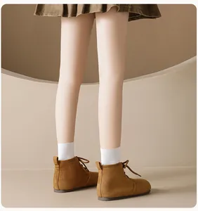 Brown suede flat boots paired with white socks and a brown pleated skirt on a model
