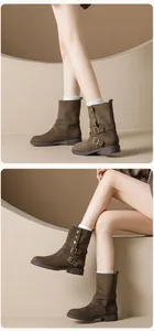 Detailed close-up of dark brown suede mid-calf boots featuring decorative metal buckles