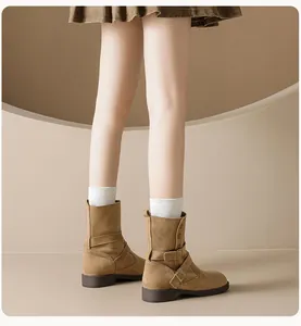Detail of khaki suede mid-calf boots featuring decorative buckles and a low brown heel