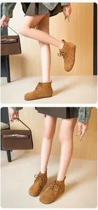 Détail de bottines à lacets en daim marron portées avec une jupe plissée foncée