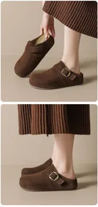 Mules en daim marron foncé avec boucles métalliques vintage sur un modèle d'automne chic