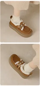 Detail der braunen Wildleder-Plateau-Clogs mit warmem Teddyfutter und Metallschnallen