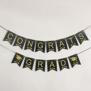 Détail de la bannière Congrats Grad noir et or avec lettres pailletées et motifs de diplôme