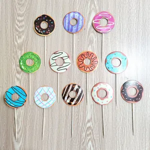 Set of 12 colorful donut cake toppers for birthday party decorations on wood surface