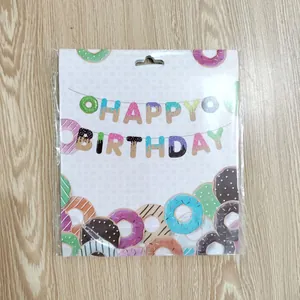 Donut themed Happy Birthday banner set in packaging on light wood background