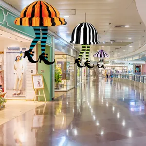 Three colorful Halloween honeycomb paper witch leg ornaments hanging in a modern mall aisle