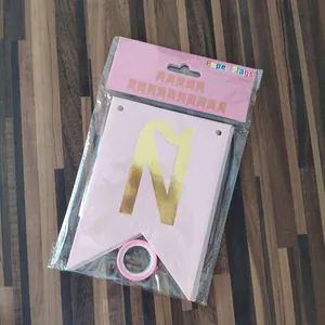 Detail of pink paper flags with gold foil letters and ribbon in retail packaging