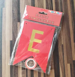 Detail of red Feliz Cumpleaños paper flags with gold lettering on wooden background