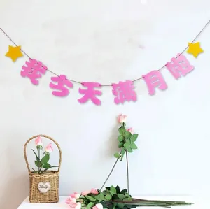 Pink felt bunting banner for baby full moon party decoration on a white wall