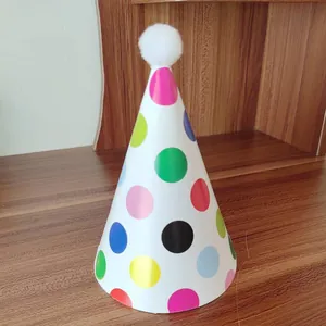 Detailed view of colorful polka dot party hat with a white plush pompom on top