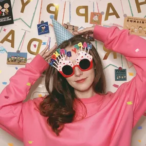 Child wearing festive birthday party cone hat and Happy Birthday cake shaped glasses