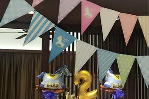 Close-up of pastel party bunting flags with rocking horse motifs and baby shower balloons