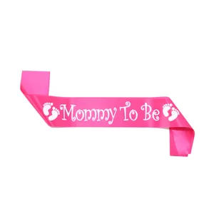 Detail of pink satin Mommy To Be sash with white lettering and baby footprints
