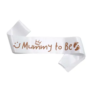 Detail of white satin Mummy to Be sash with crown and footprints for baby shower