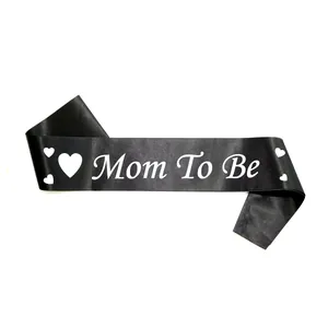 Detail of black satin Mom To Be sash with white lettering and hearts for baby showers