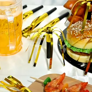 Close-up of gold foil fringed party whistles on a festive table with snacks