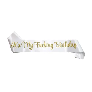 Close-up of white satin birthday sash with gold glitter It's My Fucking Birthday text