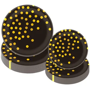 Détail d'assiettes en papier noir empilées avec pois dorés pour vaisselle de fête