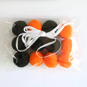 Detail von Halloween Pompons in Schwarz und Orange in Klarsichtverpackung mit weißer Schleife