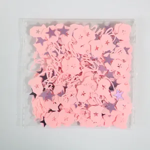 Detail of pink baby onesie and purple star confetti for gender reveal party decorations