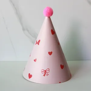 Pink cone birthday hat with plush pompom and heart patterns for children's parties