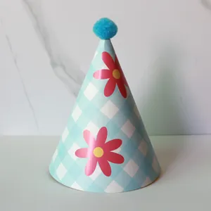 Close-up of blue checkered birthday hat with daisy flower and soft plush pom-pom top