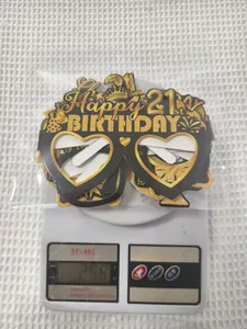 Close-up of black and gold 21st birthday party props and glasses being weighed on a scale