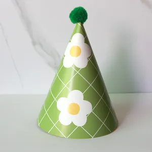 Detail of green party hat with white floral grid pattern and green pompom topper