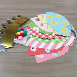 Flat lay of DIY kids party hats with cartoon patterns, velvet balls and gold crown cards