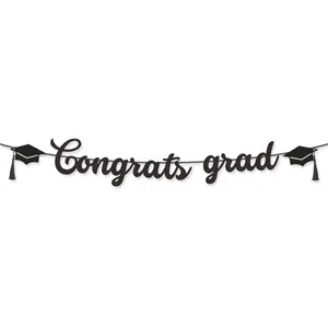 Close-up of glittery black Congrats Grad banner with graduation cap cutouts and tassels